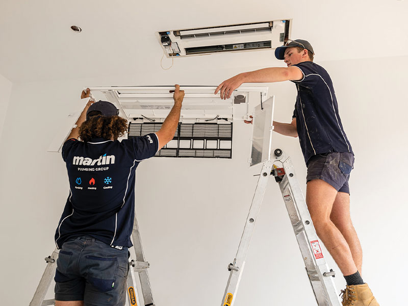 Two technicians installing ceiling vents for a home aircon systems