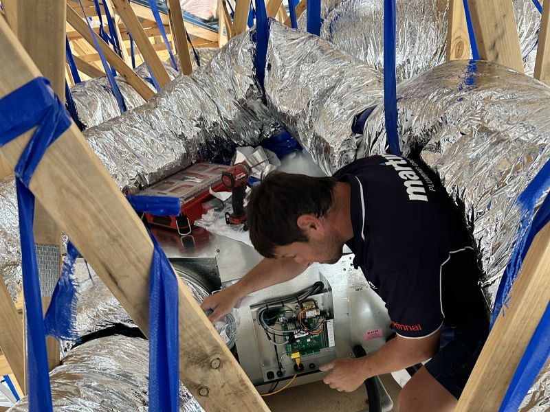 Technician installing a ducted aircon system into a roof